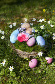 DIY Easter nest with flowers and colored eggs in the garden