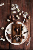 Easter place setting with brown cloth napkin, chocolate eggs, and quail eggs