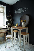 Bar table with stools in kitchen with black walls and fish motif