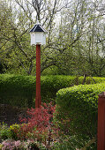 A bird house on a post in a garden