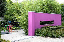 Pink wall as partition element, in the background garden square with colorful bar stools (Appeltern, Netherlands)