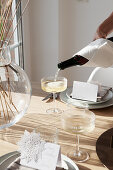 Simply decorated dining table set in natural tones, champagne being poured
