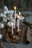 Four candle sticks in a cinnamon candle holder with larch twigs and cotton