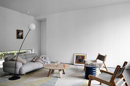 Graues Polstersofa mit Coffeetable und Stühlen im Wohnzimmer mit weißen Wänden