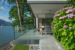 Sunlit terrace with glass balustrade panels by the lake