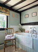 Hand-painted Chinoiserie chair in front of bathtub in bathroom with timber framed walls
