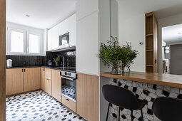 Einbauküche mit kleiner Frühstüstückstheke, grafisch wirkende schwarz-weiße Bodenfliesen