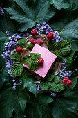 Natural raspberry soap surrounded by flowers, leaves and raspberries