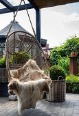 Hanging wicker chair with animal fur on the terrace