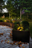 Wooden terrace with illuminated raised beds made of rusty corten steel