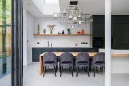 Wooden dining table extended from the kitchen island and elegant upholstered chairs in open plan living room
