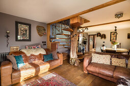 Vintage Ledercouches in offenem Wohnraum mit Holztreppe und Baumstamm