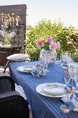 Gedeckter Tisch in Blautönen mit Rosen auf der Dachterrasse