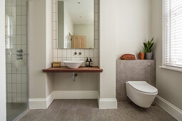 Toilet, vessel sink, above large vanity mirror and stand up shower stall in the bathroom with white wall tiles