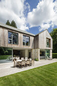 Neubauhaus mit Holzverkleidung, sonnige Terrasse mit Esstisch