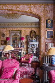Velvet furniture and antiques in Victorian room with ornate wallpaper