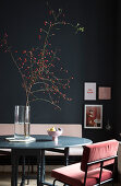 Dining area with black table and velvet chairs in front of black wall