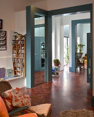 Open-plan living room with blue door frames and dark parquet flooring
