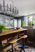 Industrial table with vintage stools, above it modern lamp in the kitchen