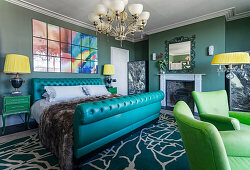 Queen bed with a turquoise capitone upholstered head and foot board, green armchairs in the foreground