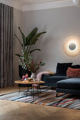 Wall mounted light above velvet sofa, side tables, and indoor plant
