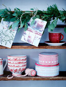Rustic wooden shelf with Christmas crockery and garland of leaves