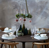 Gedeckter Weihnachtstisch mit weißem Geschirr, darüber hängender Adventskranz
