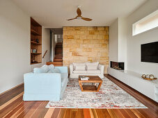 Upholstered sofas in the living room with sandstone wall and parquet floor