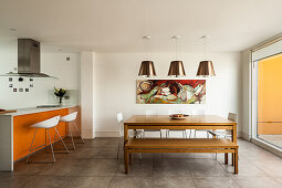 A dining table with a bench and white chairs, and a breakfast bar with an orange front and bar stools
