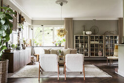 Living room in natural colors, with seating area, sideboard, and vintage glass cabinets