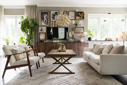 Wohnzimmer mit hellen Sitzmöbeln, Holz-Couchtisch und Bildersammlung über dem Sideboard