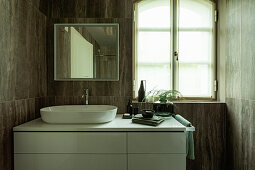A washstand in a bathroom with dark tiles