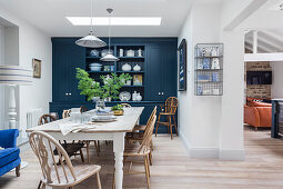 Long table with chairs and blue built-in cupboard in the dining area with skylight
