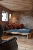 Sofa mit Kissen und Ledersessel in einer Holzhütte