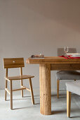 Esstisch aus Massivholz mit gepolsterten Stühlen und ein Holzstuhl auf Betonboden