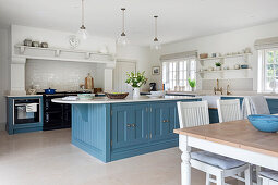 Spacious white kitchen with dining area and center kitchen island with blue fronts