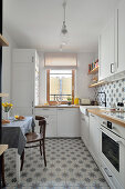 White fitted kitchen cabinets with dining area and patterned tiles