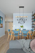 View of dining area with blue chairs in front of light blue wall in open plan living room