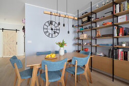 Dining area with blue chairs in front of floor-to-ceiling shelves