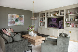 Graue Sofagarnitur, Couchtisch, großformatiges Gemälde an der Wand und Regalschrank im Wohnzimmer