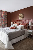 Doppelbett mit hohem Kopfteil und passenden Kissen im Schlafzimmer in warmen Rottönen