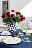 Gedeckter Tisch mit Rosenstrauß auf der Terrasse