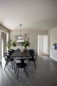Black table and designer chairs in dining room with concrete floor
