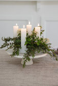Candle arrangement on cake plate with fresh greenery