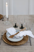 Dining table set with ceramic bowl, wooden spoon, glasses and candlestick