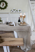 Dining table decorated with linen, candles and fresh branches
