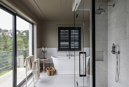 Duschbereich mit Verglasung und freistehende Badewanne in großzügigem Badezimmer mit Balkon