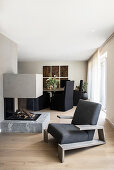 Designer armchairs in front of fireplace, in the background an elegant dining area
