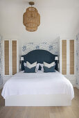 Doppelbett in hellem, lichtdurchflutetem Schlafzimmer mit blau-weißer Tapete