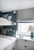 Bunk bed and bedside cabinet in narrow room in blue and white tones